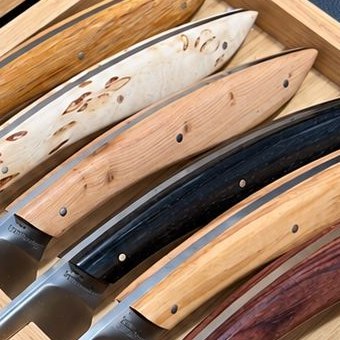 Détail de manches en bois clair et en bois sombre, dans un coffret en bois