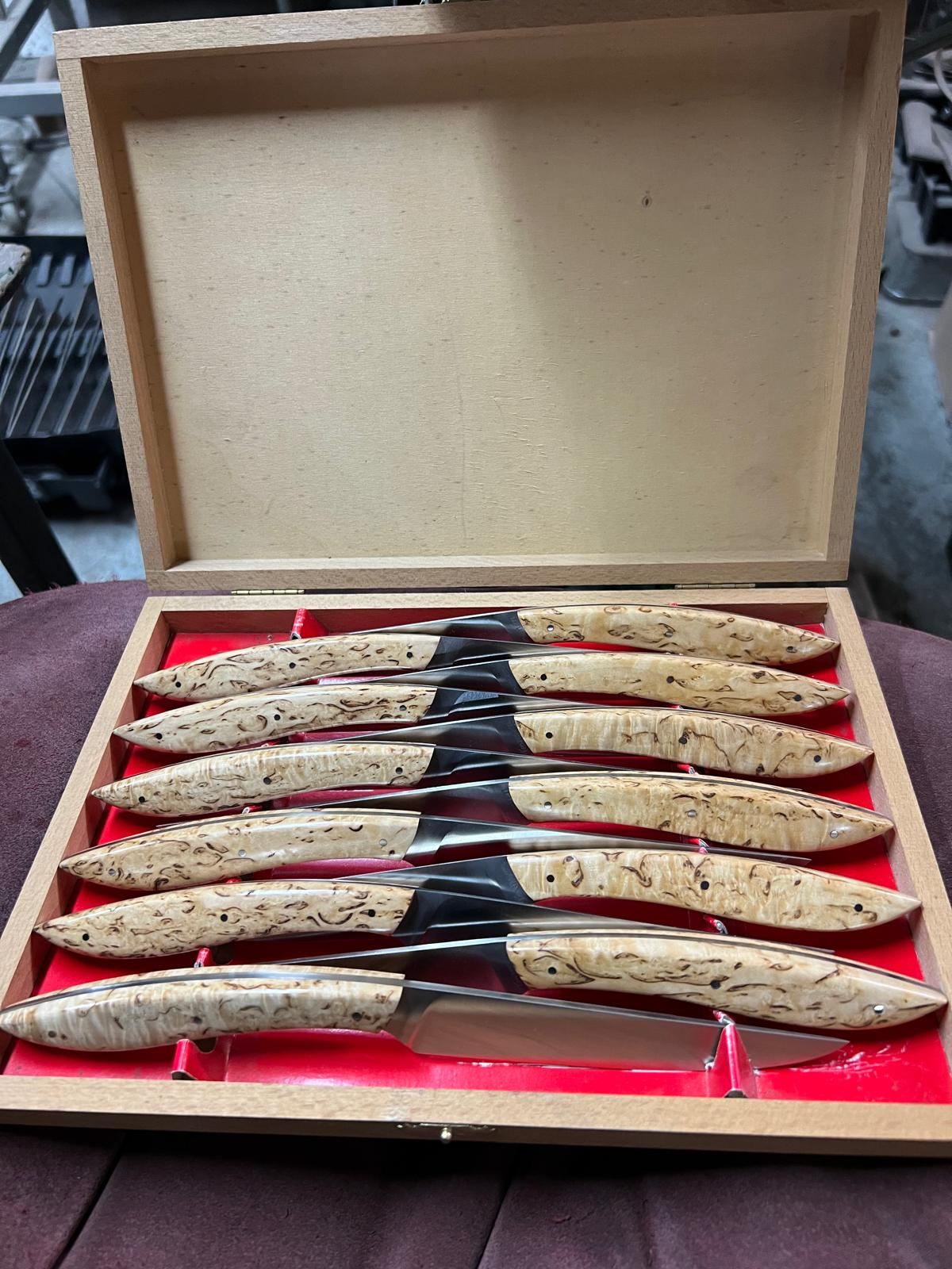 Coffret de couteaux aux manches clairs sur fond rouge