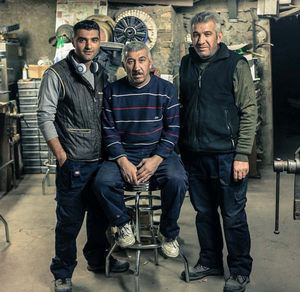 Les trois frères Teymen, debout et assis dans leur atelier